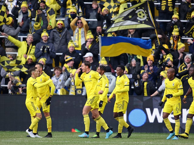 Columbus Crew forward Miguel Berry (27) reacts after scoring a goal against the Vancouver Whitecaps as a fan waves a flag of Ukraine during the first half at Lower.com Field on February 26, 2022
