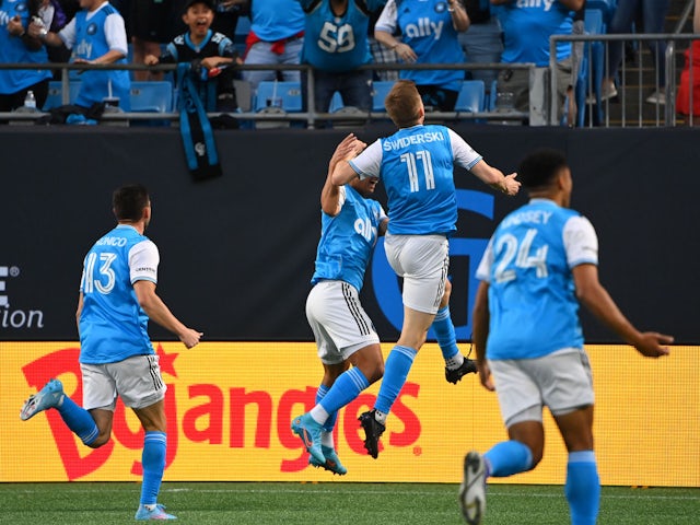 Charlotte FC forward Karol ?widerski (11) celebrates with teammates after scoring a goal is in the background in the first half at Bank of America Stadium on March 19, 2022
