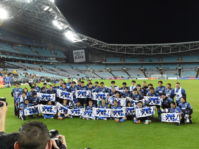 Japan players pose with banners as they celebrate after the match on March 24, 2022