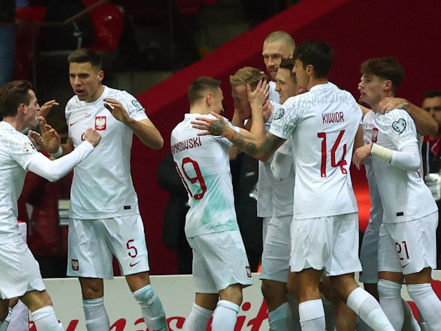 Polský hráč Karol Swiderski slaví 27. března 2023 svůj první gól s Przemyslawem Frankowskim a jeho spoluhráči.