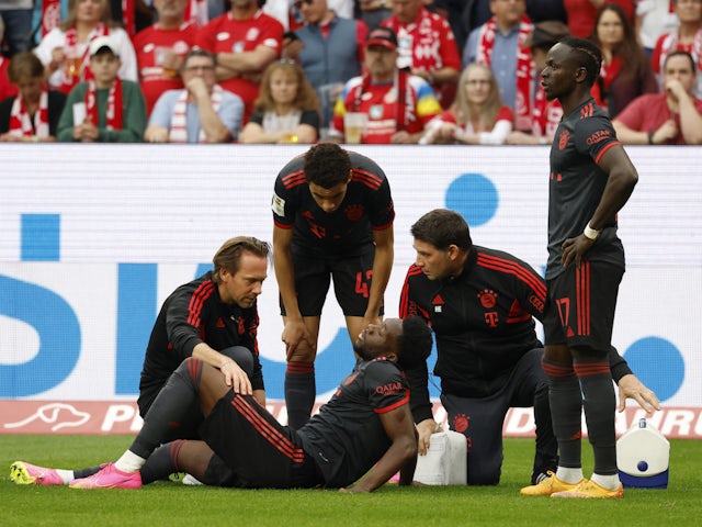 Bayern Munich's Alphonso Davies receives medical attention after sustaining an injury as Jamal Musiala and Sadio Mane look on on April 22, 2023