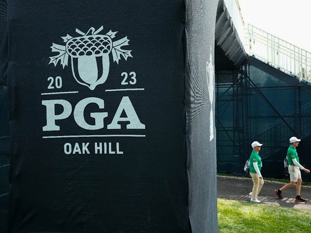 Volunteers walk behind the 1st tee during a practice round of the PGA Championship golf tournament at Oak Hill Country Club on May 15, 2023