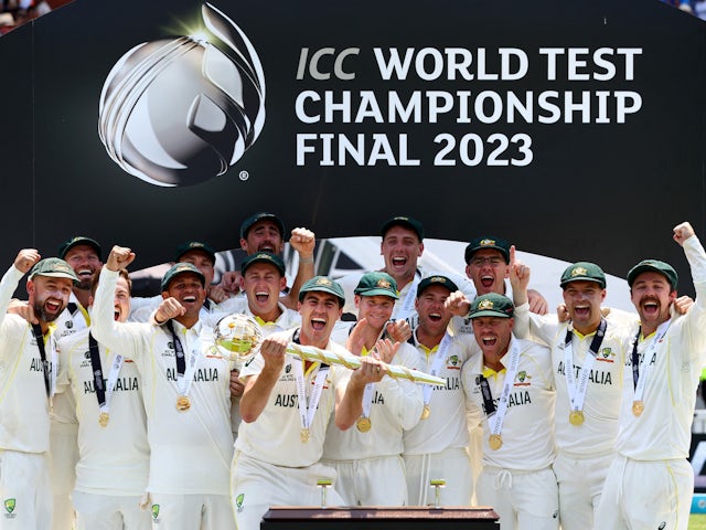 Australia's Pat Cummins celebrates with the ICC Test Mace on the podium along with teammates after winning the World Test Championship final on June 11, 2023
