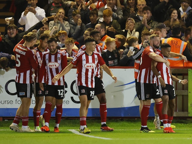 Exeter City's Demetri Mitchell celebrates scoring their first goal with teammates on September 26, 2023