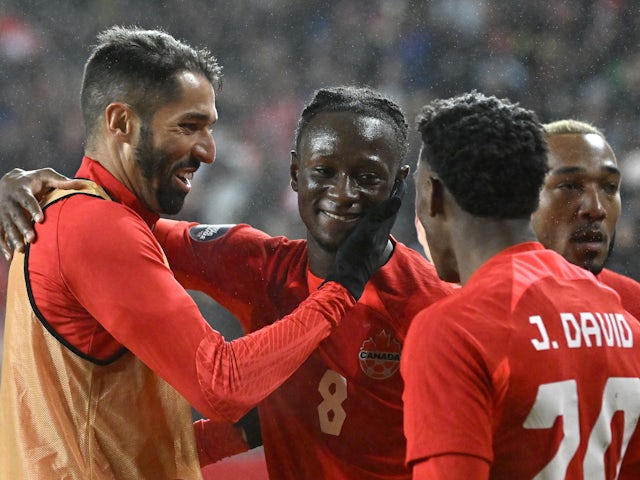 Canada midfielder Ismael Kone (8) celebrates with forward Jonathan David (20) and defender Steven Vitoria (5) on November 22, 2023