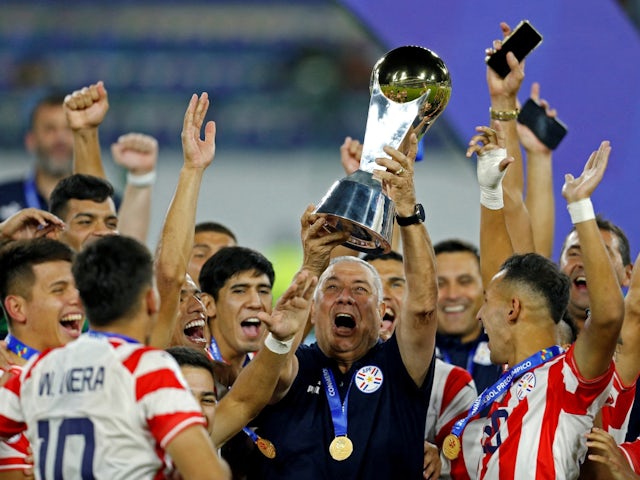 Paraguay Under-23s coach Carlos Jara Saguier and players celebrate winning the tournament with the trophy after qualifying for the Paris Olympics 2024 on February 11, 2024
