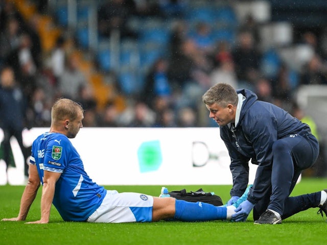 Sam Hughes of Stockport County receives treatment for an in jury during his side's match against Blackburn Rovers, on August 13, 2024