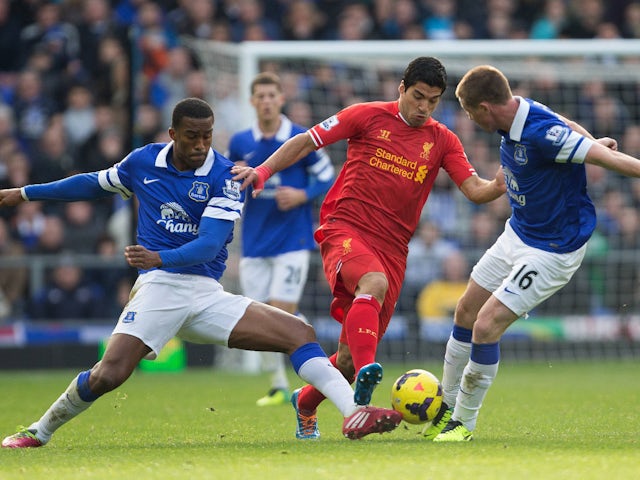 Liverpool's Luis Suarez with Everton's Sylvain Distin and James McCarthy on November 23, 2013